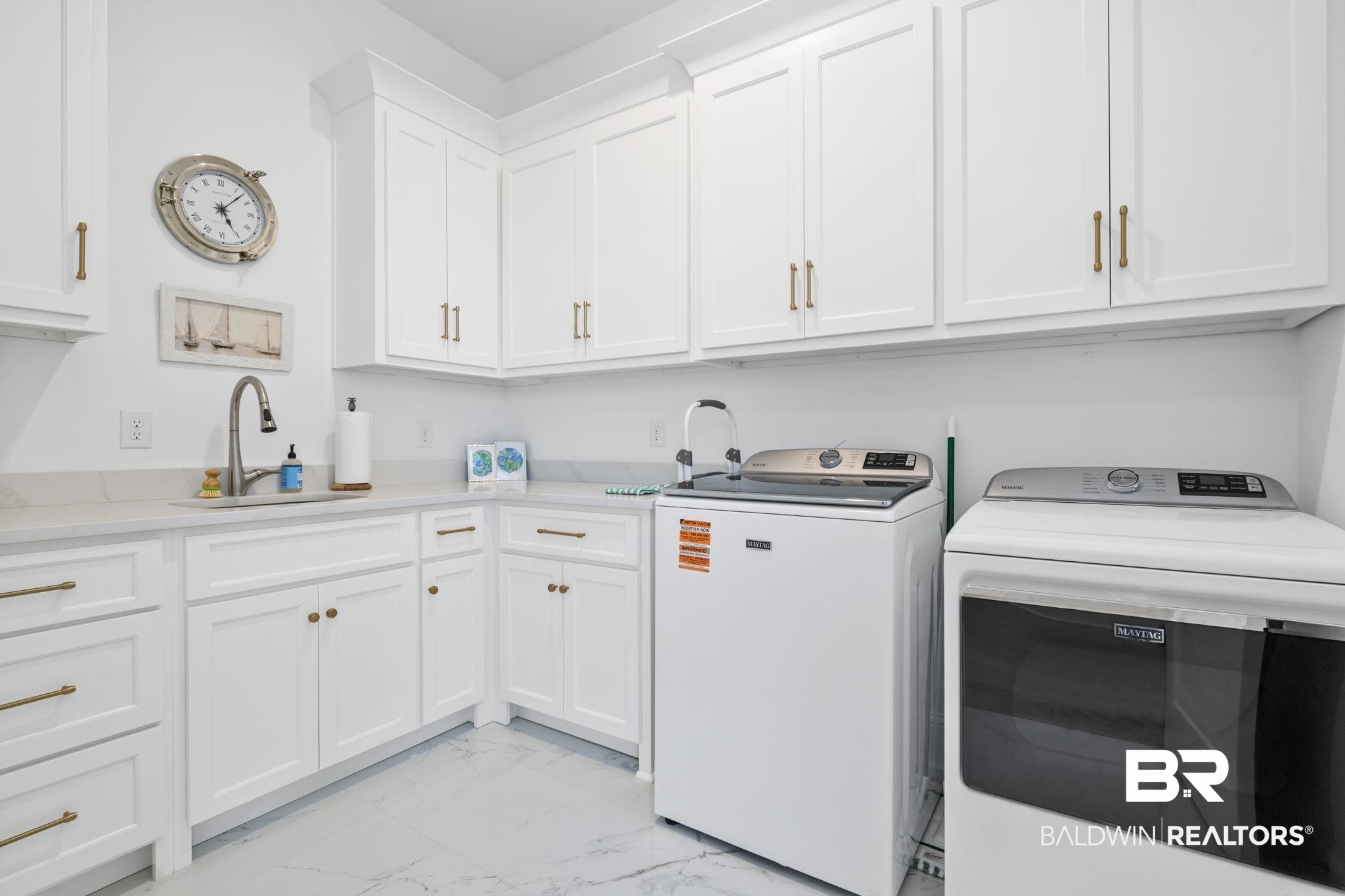 30313 River Road Orange Beach, AL 36561 - Photo 28 of 50 Laundry room featuring light marble finish flooring, washing machine and clothes dryer, and cabinet space