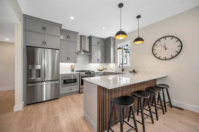 a kitchen with kitchen island stainless steel appliances a stove a sink a refrigerator and chairs