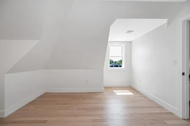 a view of a hallway with wooden floor and a bathroom