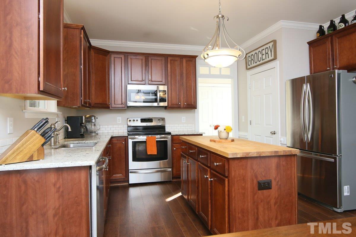 9212 Pennythorne Court Raleigh, NC 27615 - Photo 12 of 25 a kitchen with stainless steel appliances granite countertop a refrigerator a sink dishwasher a stove with wooden cabinets and floor