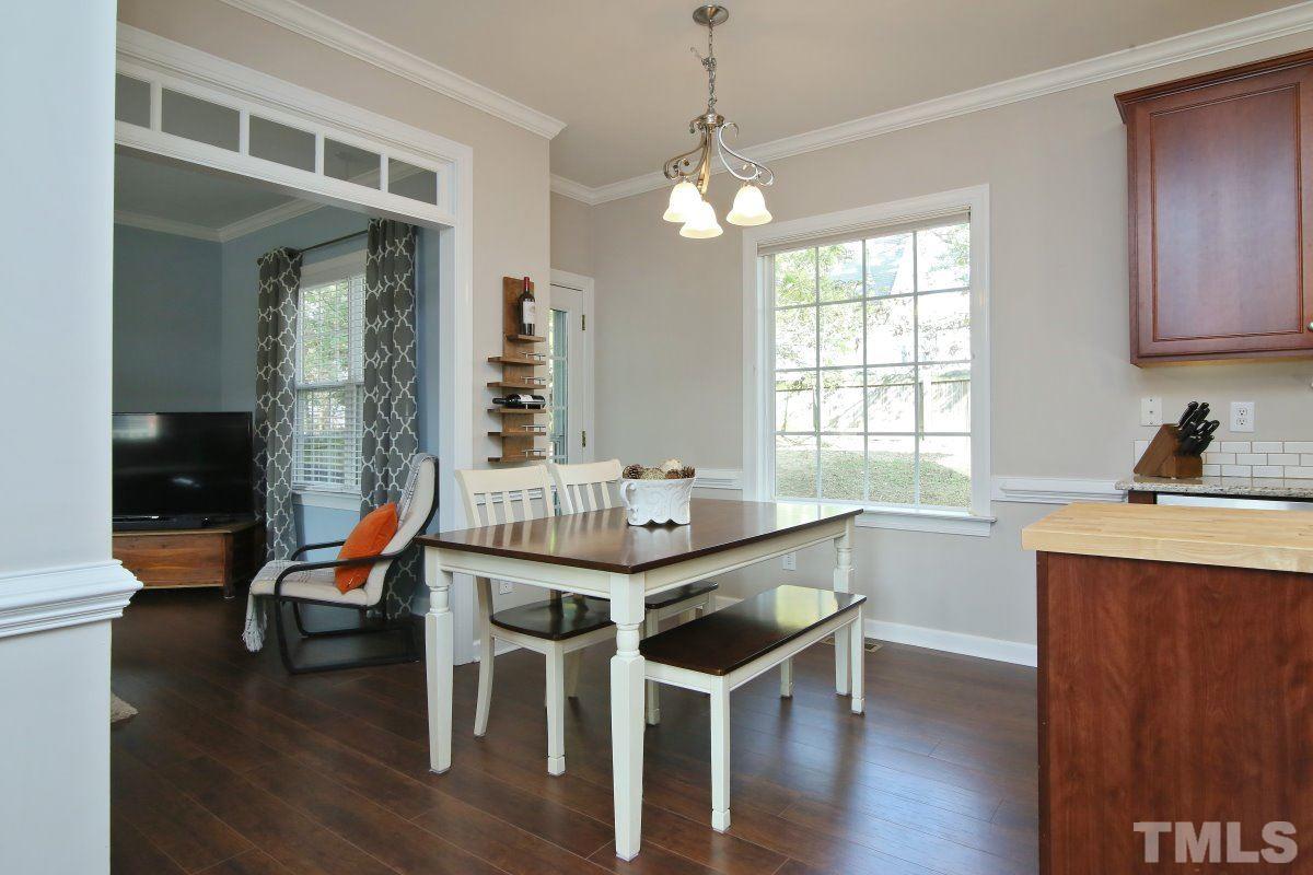 9212 Pennythorne Court Raleigh, NC 27615 - Photo 14 of 25 a dining room with wooden floor a chandelier a wooden table and chairs