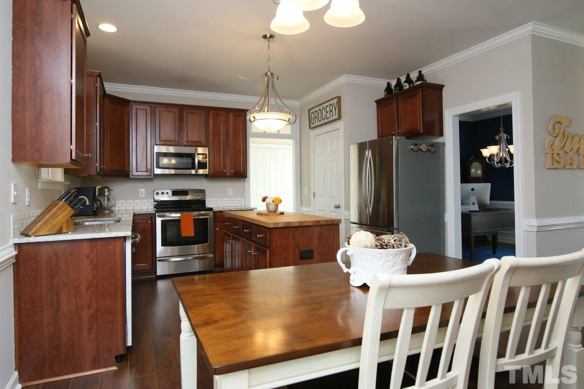 9212 Pennythorne Court Raleigh, NC 27615 - Photo 15 of 25 a kitchen with stainless steel appliances granite countertop a refrigerator a stove top oven a sink dishwasher and wooden cabinets