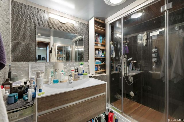 a bathroom with a mirror vanity and a glass shower door