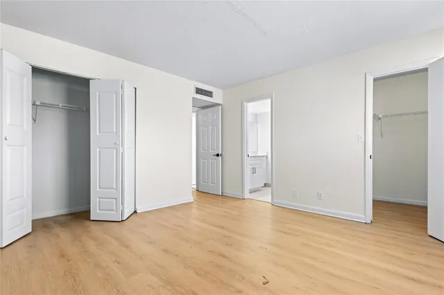 an empty room with wooden floor & closet area