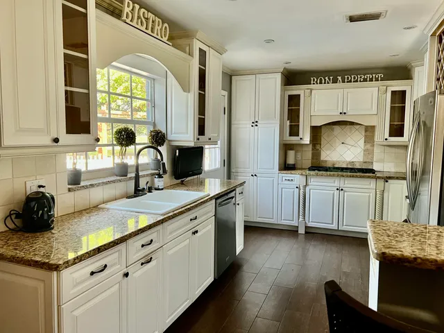 a kitchen with granite countertop a sink cabinets and stainless steel appliances