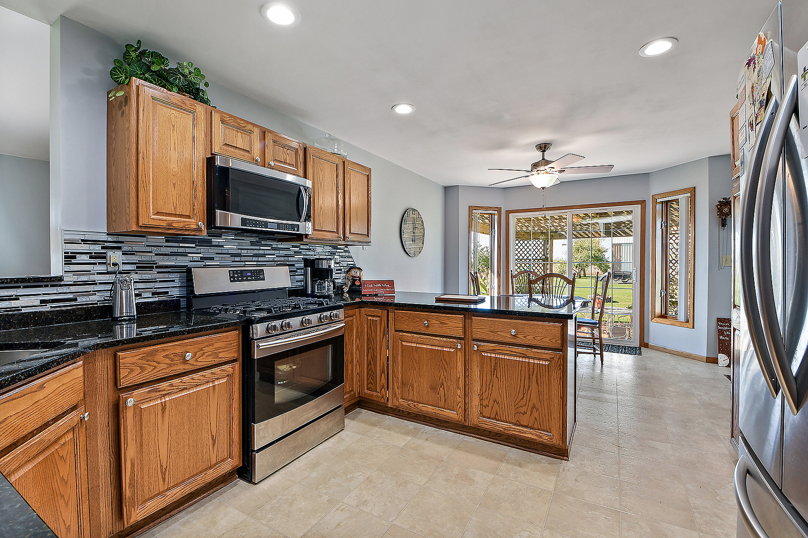 32220 South Cedar Road Manhattan, IL 60442 - Photo 9 of 46 a kitchen with stainless steel appliances granite countertop a stove top oven a sink dishwasher a dining table and chairs with wooden floor
