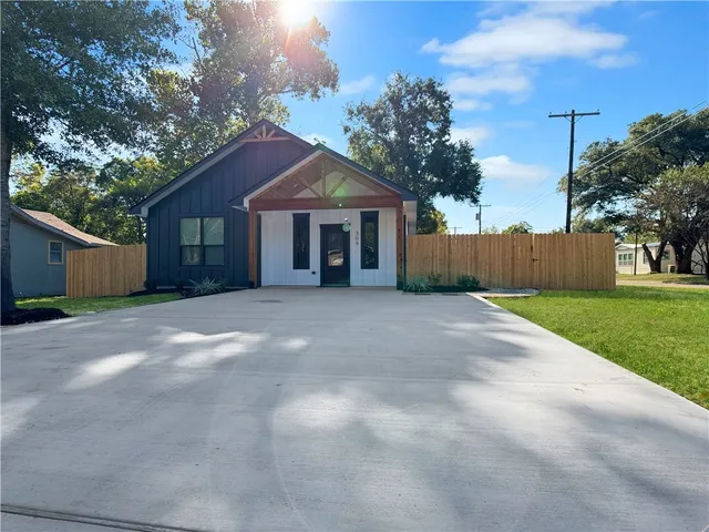 a view of a house with a yard and large tree