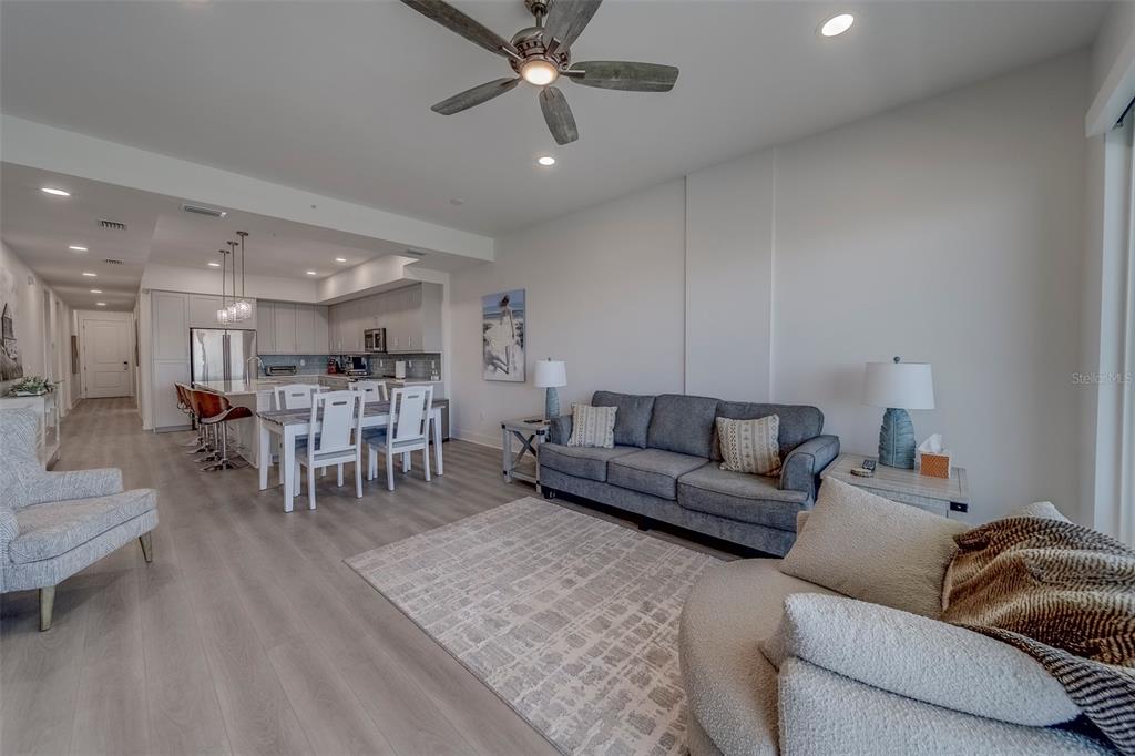 400 150th Avenue, Unit 301 Madeira Beach, FL 33708 - Photo 15 of 66 a living room with furniture and a dining table with wooden floor