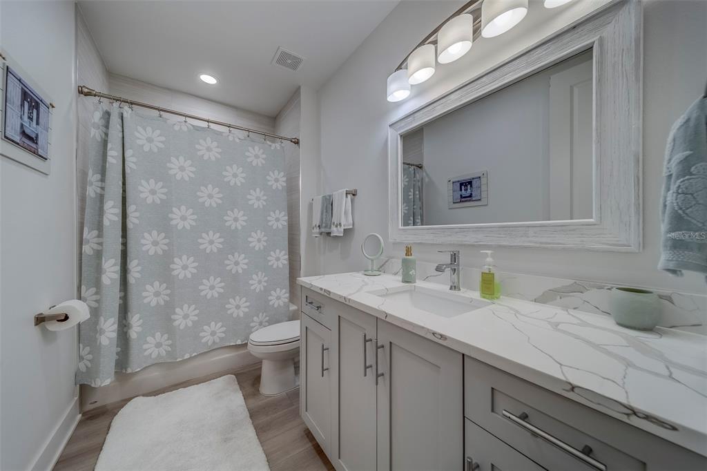 400 150th Avenue, Unit 301 Madeira Beach, FL 33708 - Photo 39 of 66 a bathroom with a granite countertop sink a toilet a mirror and shower