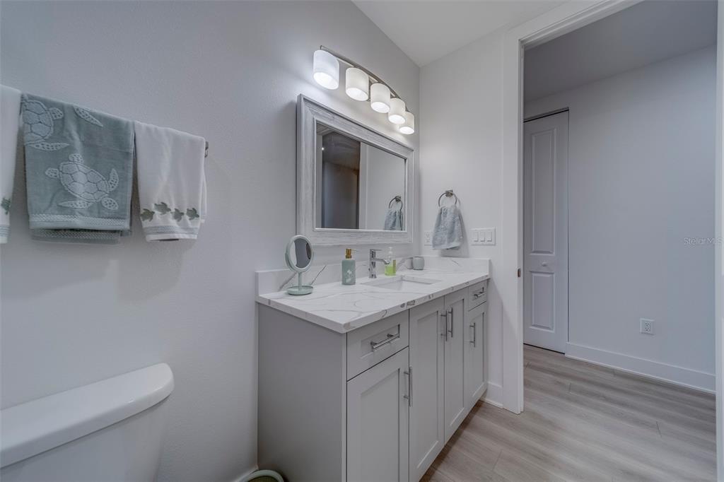 400 150th Avenue, Unit 301 Madeira Beach, FL 33708 - Photo 41 of 66 a bathroom with a granite countertop toilet a sink and a mirror
