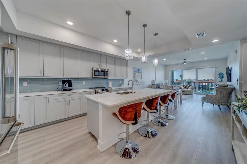 400 150th Avenue, Unit 301 Madeira Beach, FL 33708 - Photo 6 of 66 a kitchen with stainless steel appliances granite countertop a table chairs sink and cabinets