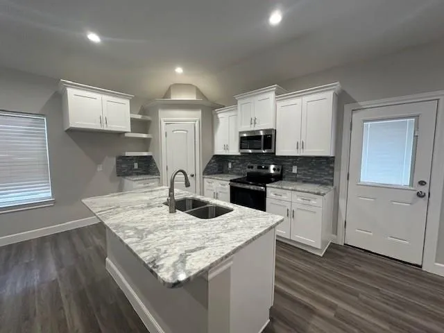 a kitchen with granite countertop white cabinets sink and stainless steel appliances