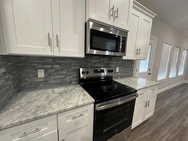 a kitchen with granite countertop white cabinets and black appliances