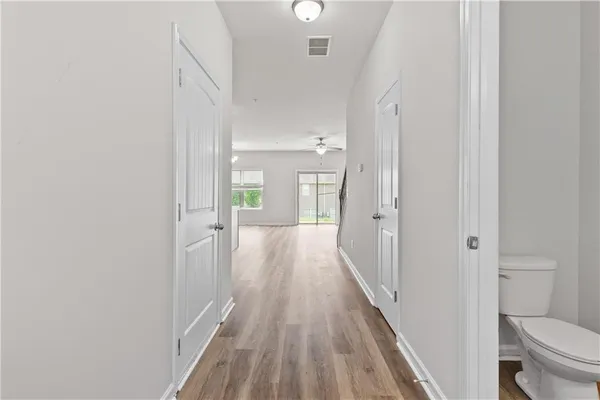 a view of a hallway with wooden floor and a bathroom