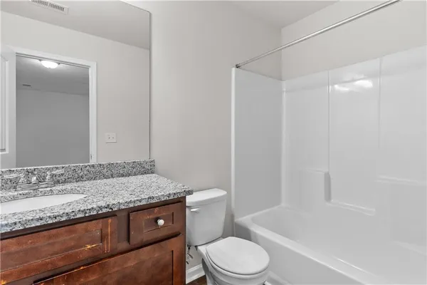 a bathroom with a granite countertop sink a toilet and bathtub