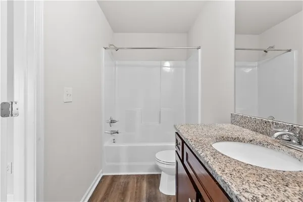 a bathroom with a granite countertop sink a toilet and shower