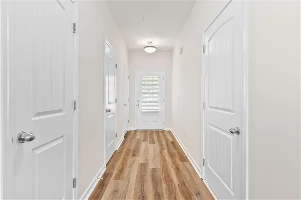 a view of a hallway with wooden floor and a bathroom