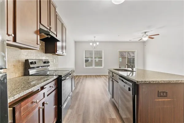 a kitchen with granite countertop stainless steel appliances a sink stove top oven and cabinets