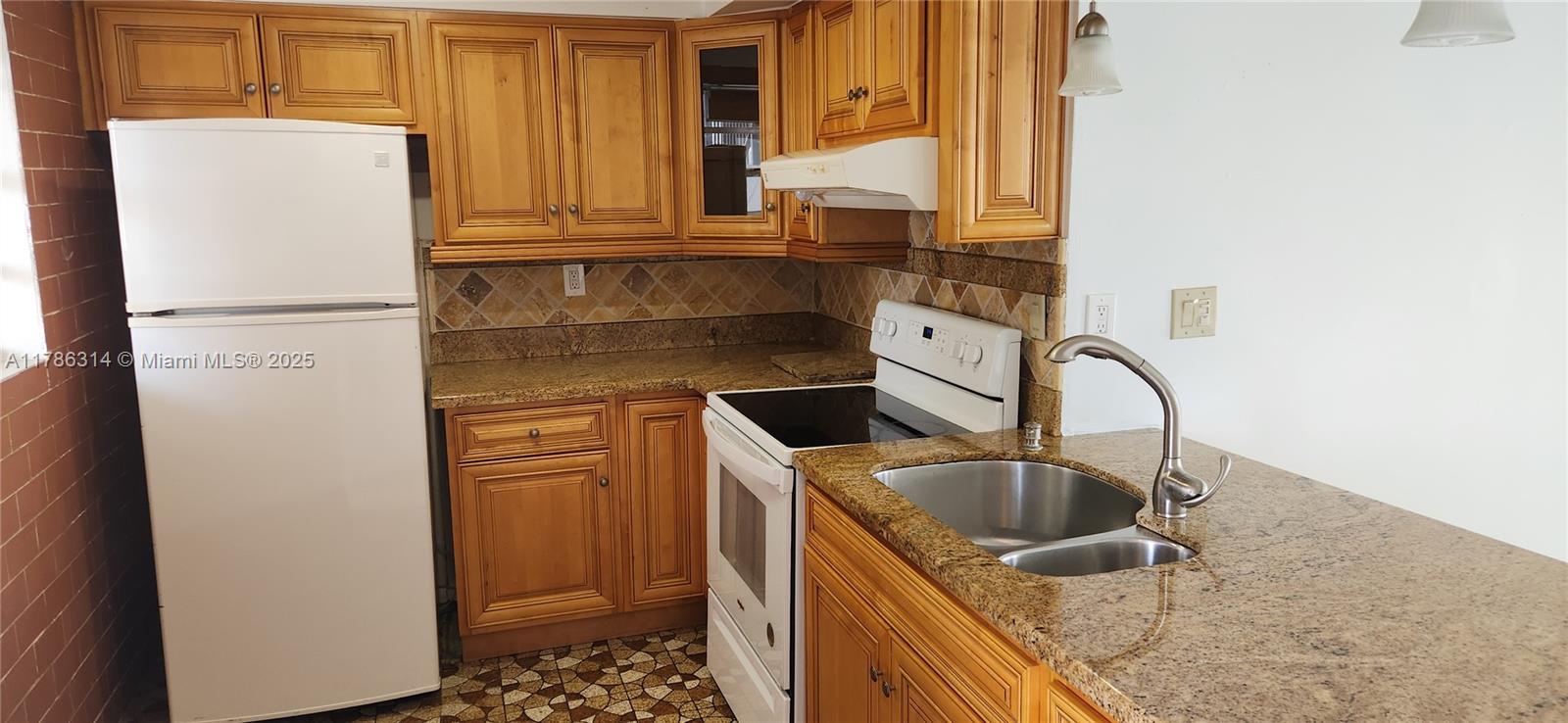 14195 Southwest 87th Street, Unit B306 Miami, FL 33183 - Photo 2 of 13 a kitchen with a sink a refrigerator and cabinets