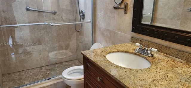 a bathroom with a granite countertop sink toilet a mirror and shower