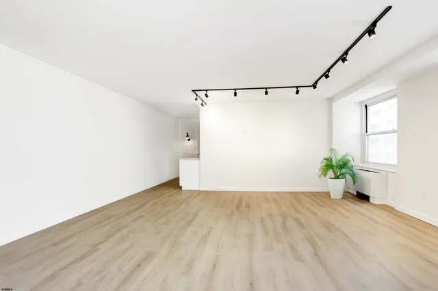 a view of an empty room with wooden floor and a window