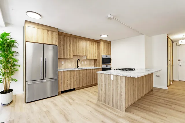 a kitchen with stainless steel appliances granite countertop a refrigerator a stove and a wooden floors