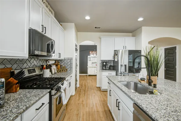 a kitchen with granite countertop a sink a counter space stainless steel appliances and cabinets