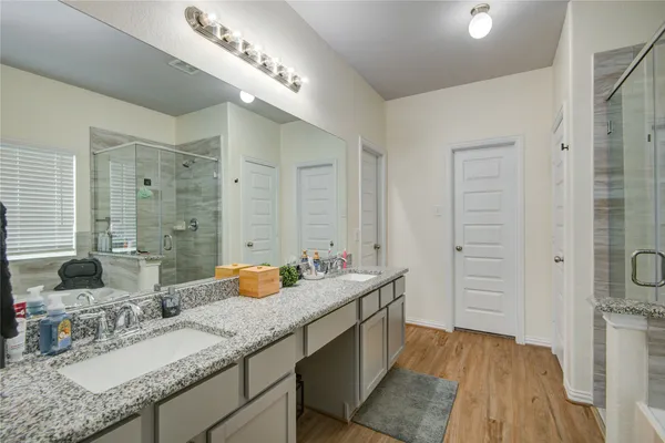 a bathroom with a sink double vanity granite tub shower and a mirror