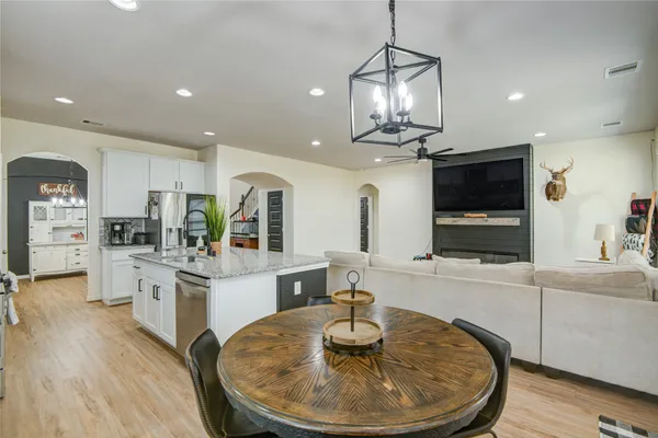 a kitchen with stainless steel appliances kitchen island granite countertop a stove a oven a dining table and chairs with wooden floor