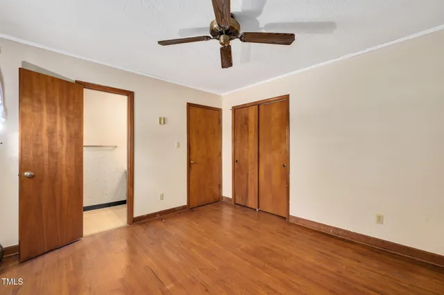 a view of an empty room with window a ceiling fan and wooden floor
