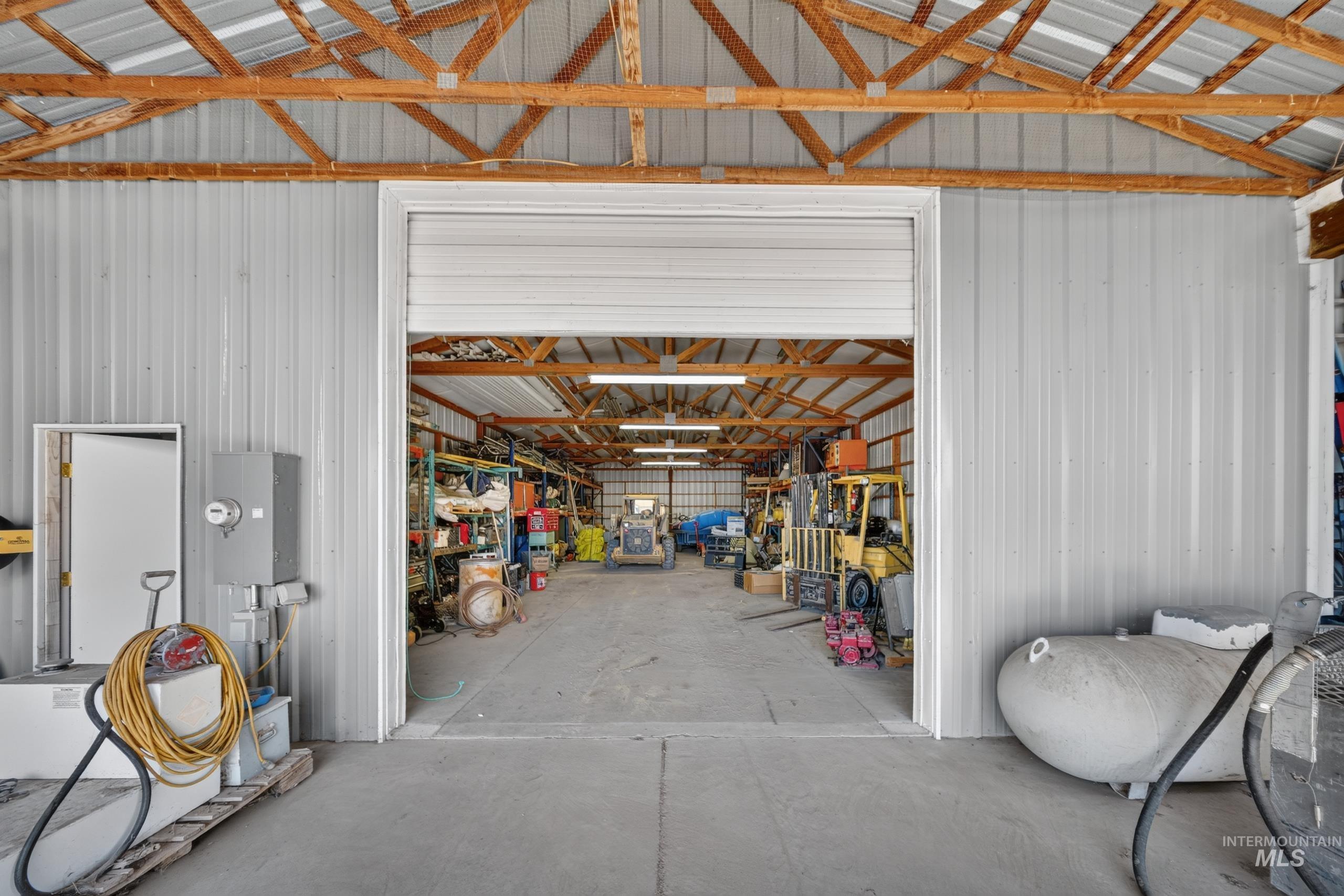 5540 Finley Road Fruitland, ID 83619 - Photo 48 of 50 Expansive utility building featuring a corrugated metal exterior, exposed wood beam ceiling, concrete flooring, and a large roll-up entry door