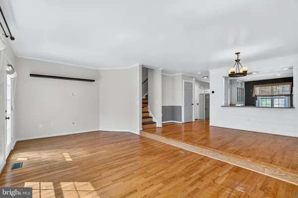 a view of a livingroom with wooden floor and kitchen space