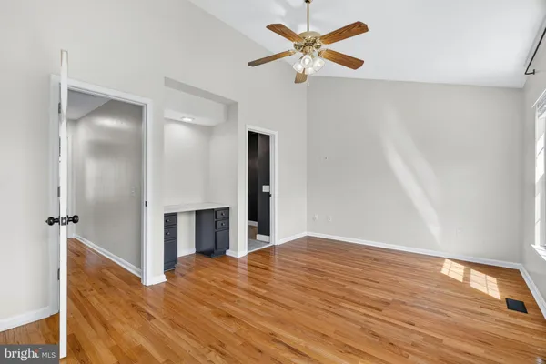 an empty room with wooden floor and a ceiling fan