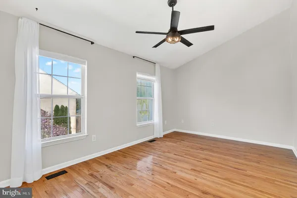 a view of empty room with wooden floor and fan
