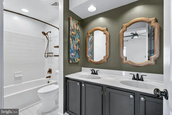 a bathroom with a double vanity sink toilet mirror and bathtub
