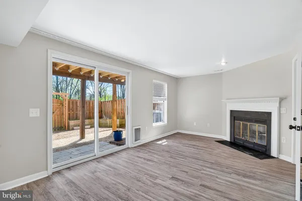 a view of an empty room with wooden floor and a fireplace