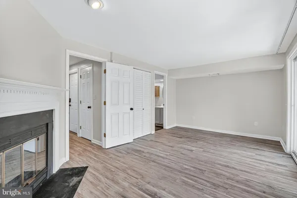 a view of an empty room with wooden floor fireplace and a window