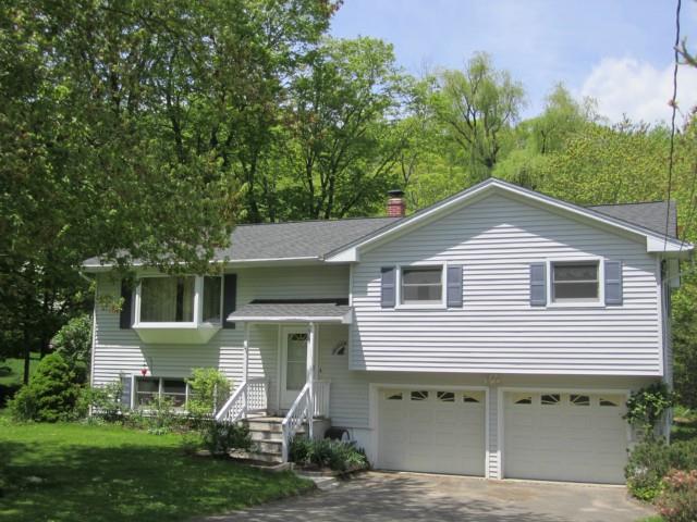 a view of a house with a yard plants and large tree