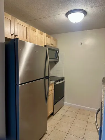 a view of a refrigerator in kitchen and an empty room