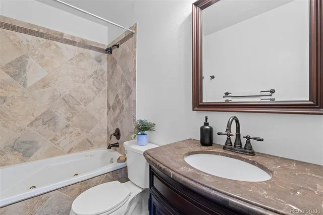 a bathroom with a granite countertop sink toilet a mirror and bathtub