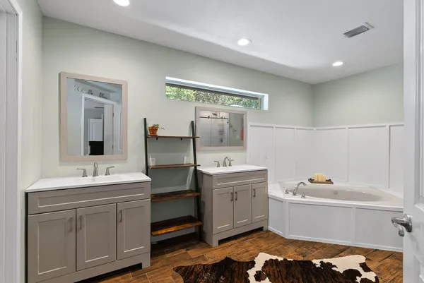 a bathroom with a double vanity sink mirror and bathtub