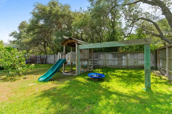 a view of a backyard with a slide trees and wooden fence