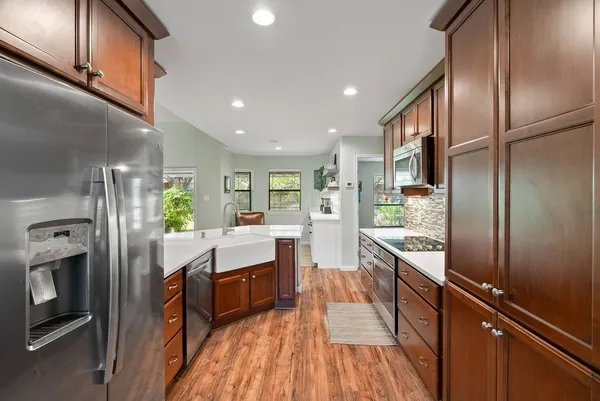 a kitchen with kitchen island wooden floor center island and stainless steel appliances