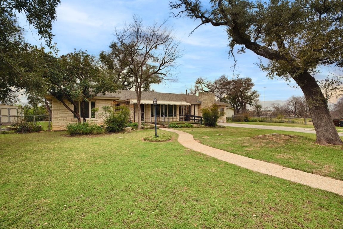 a view of a house with a big yard and large trees