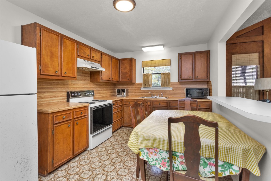7415 Honea Egypt Road Montgomery, TX 77316 - Photo 23 of 50 a kitchen with stainless steel appliances granite countertop a refrigerator a stove a sink dishwasher and white cabinets with wooden floor