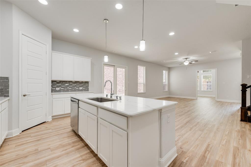 628 Ansley Way Allen, TX 75013 - Photo 5 of 20 Kitchen island with white cabinetry and an undermount sink, complemented by pendant lighting