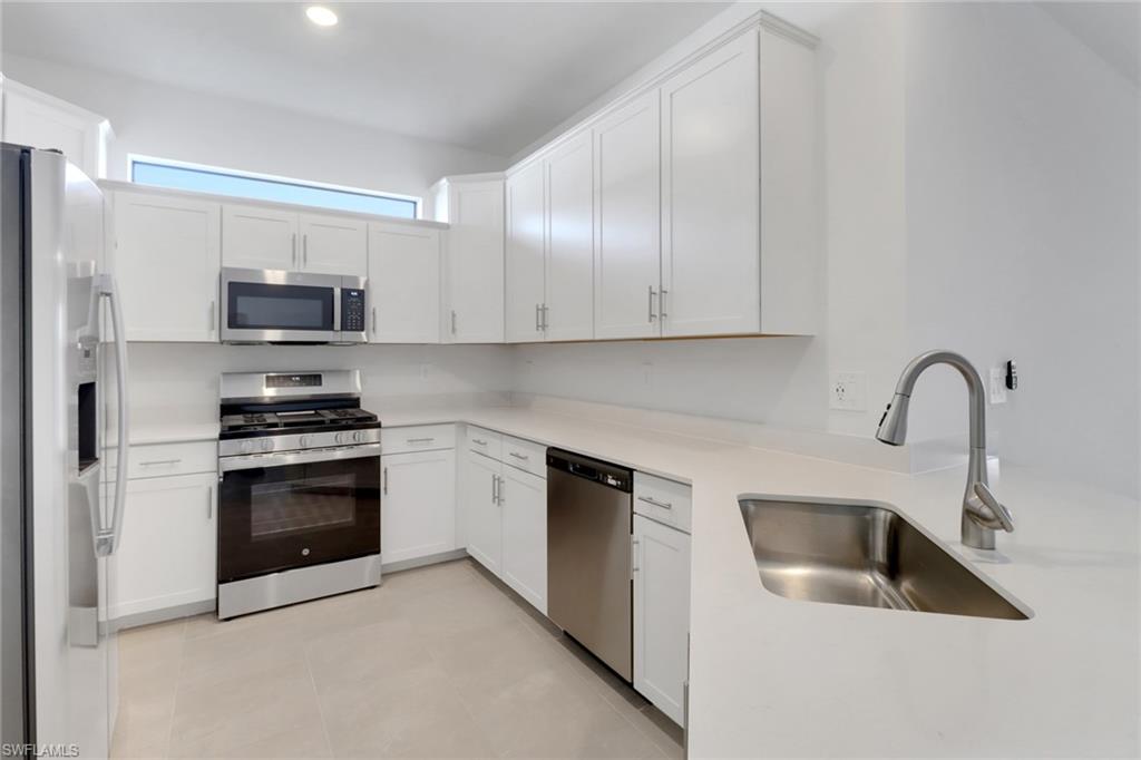 19513 Hinkley Drive Estero, FL 33928 - Photo 7 of 38 a kitchen with granite countertop a sink and a stove top oven
