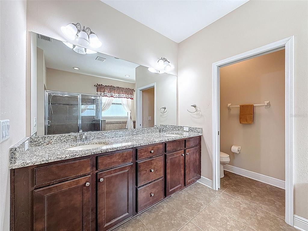 335 Cockle Shell Loop Apollo Beach, FL 33572 - Photo 30 of 90 a bathroom with a granite countertop sink a large mirror and a shower