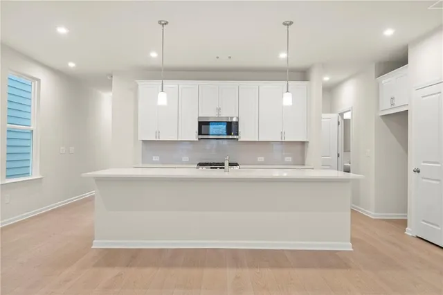 a large kitchen with granite countertop a stove a sink a refrigerator and a fireplace