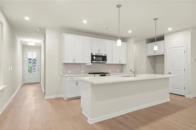 a kitchen with kitchen island a sink stainless steel appliances and white cabinets